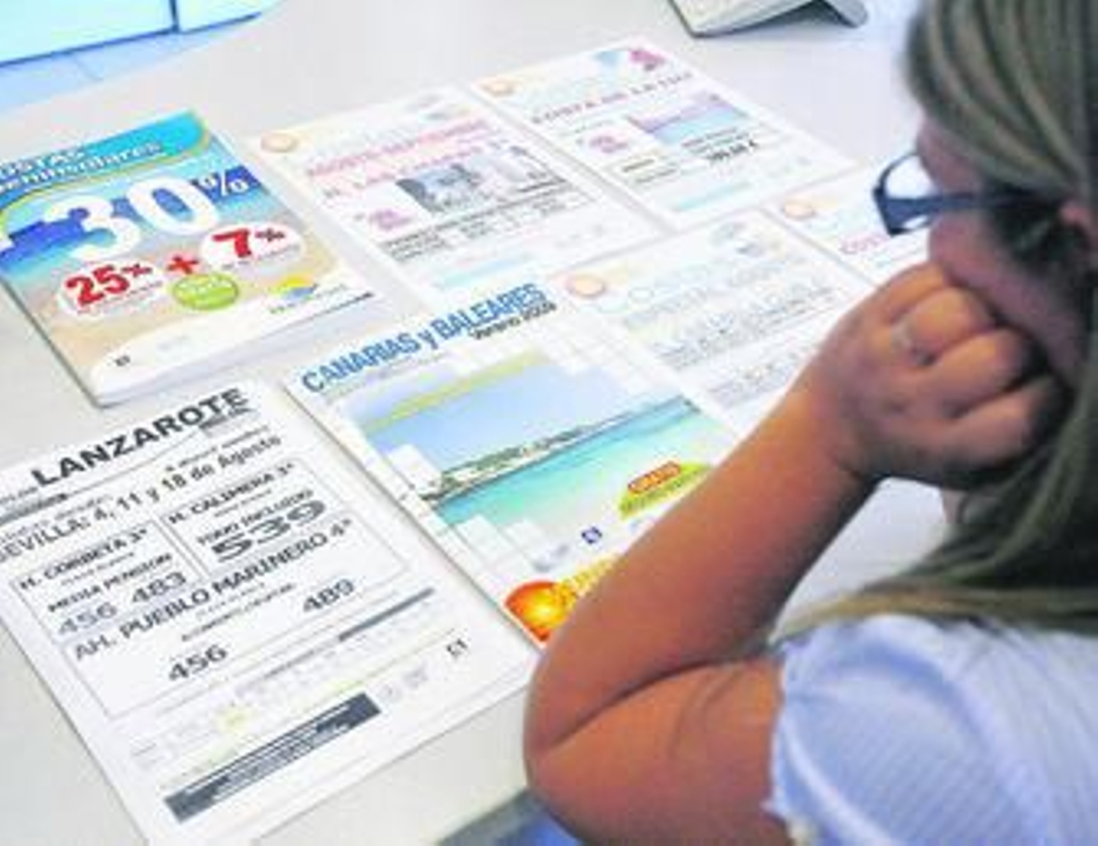 Una gaditana contempla las distintas ofertas que les enseña la agencia de viajes