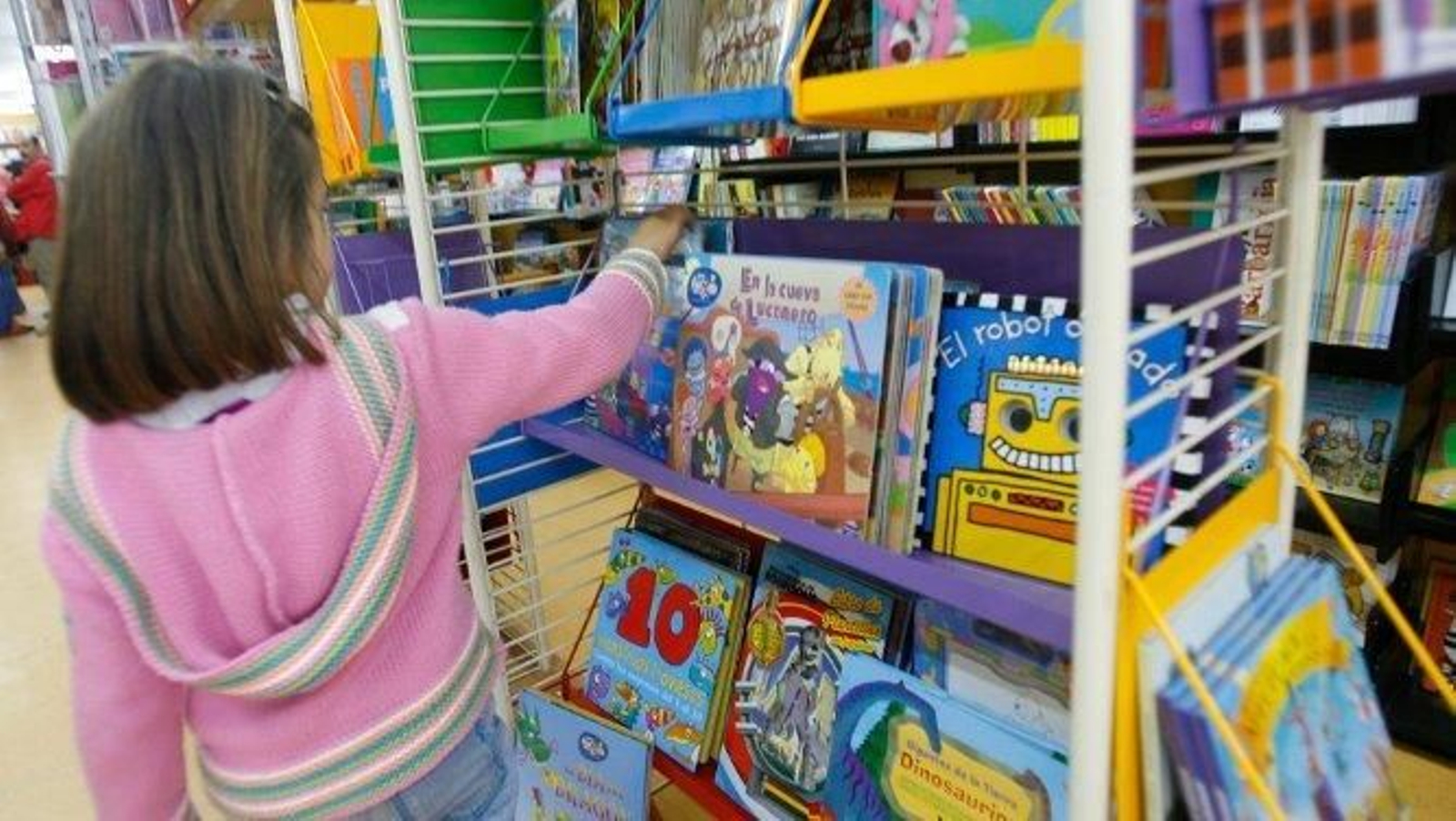 Una niña analiza las posibilidades que le ofrece una estantería de la librería infantil Qüentum.