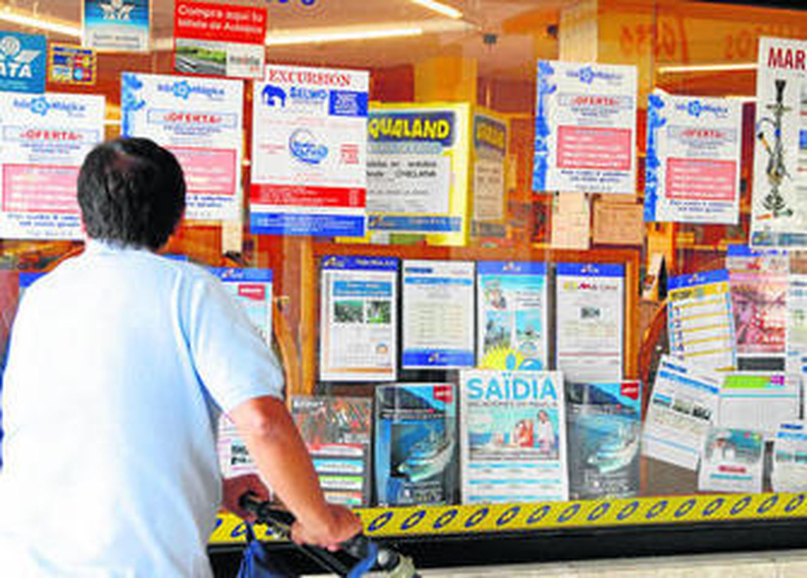 Un cliente contempla el escaparate de una agencia de viajes en busca de ofertas turísticas.
