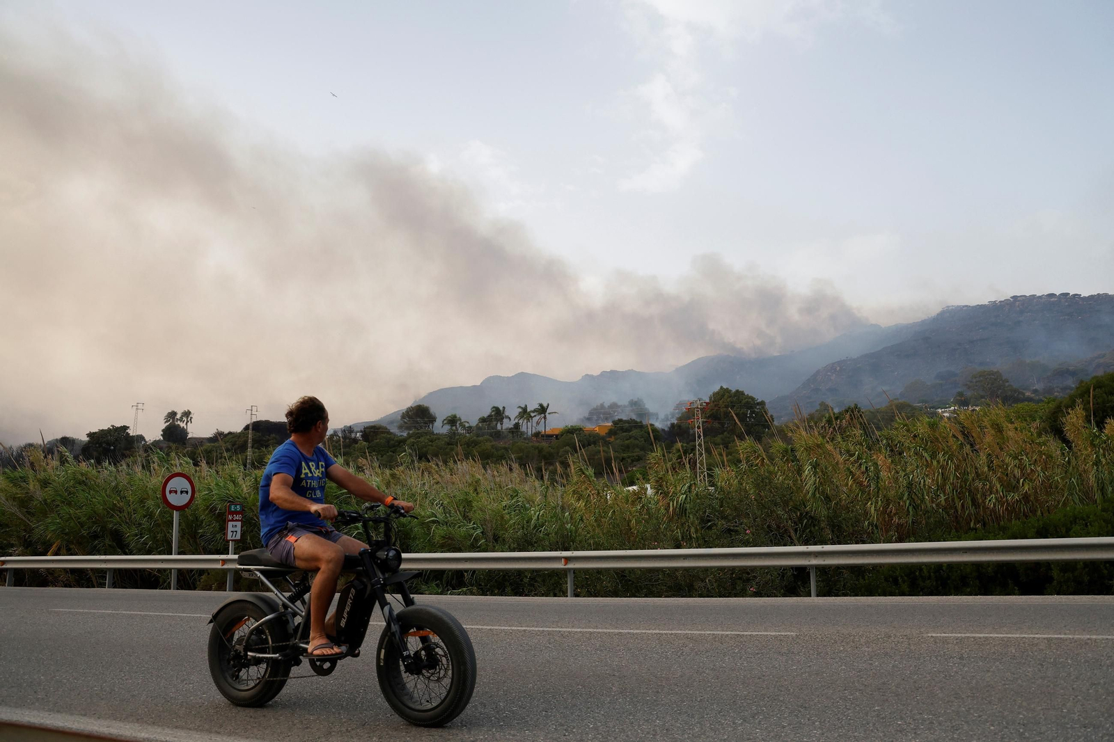 Un hombre sobre una moto observa un incendio en Tarifa este mes de agosto.
