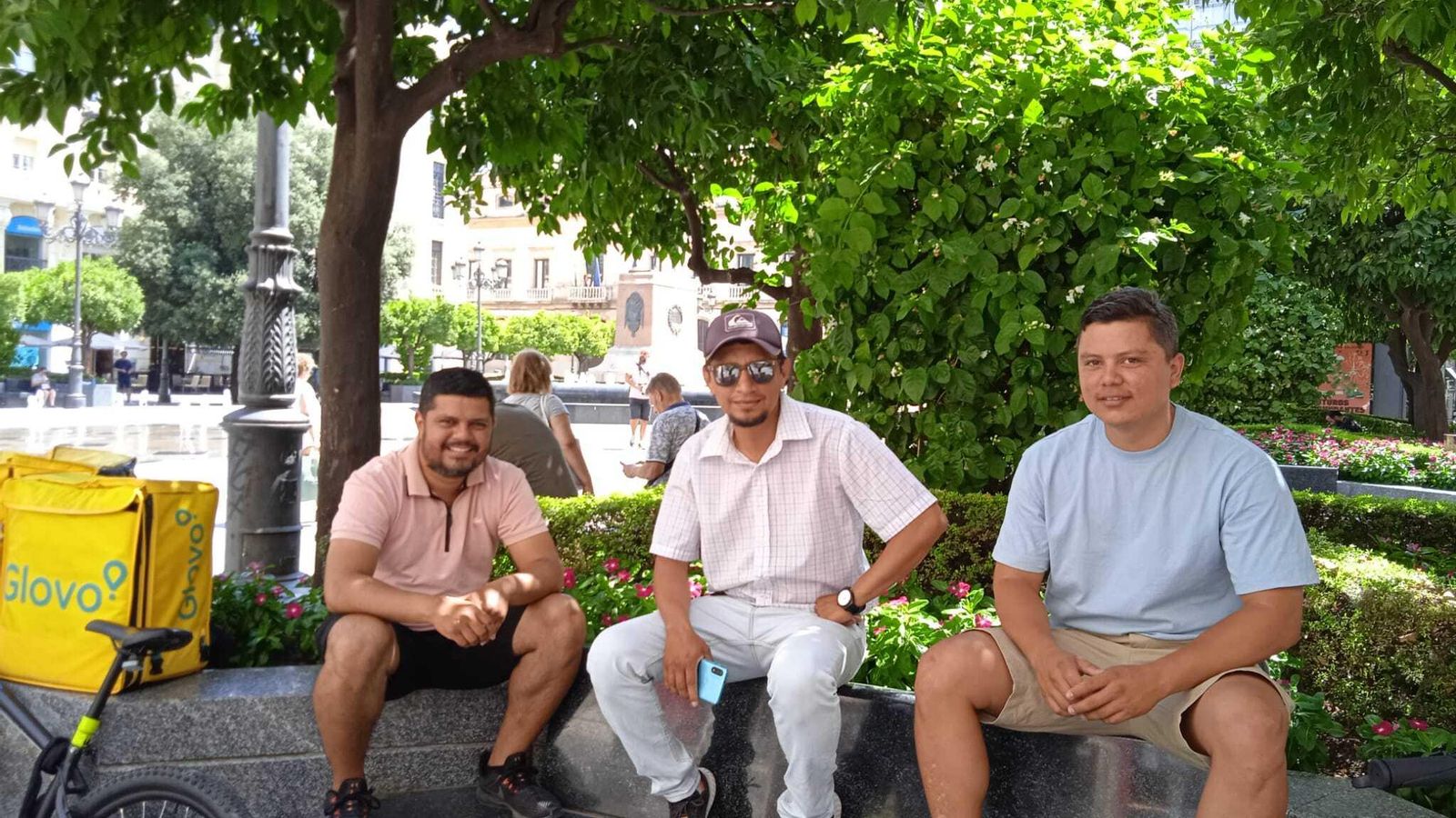 Repartidores de comida a domicilio en Córdoba descansan a la sombra.