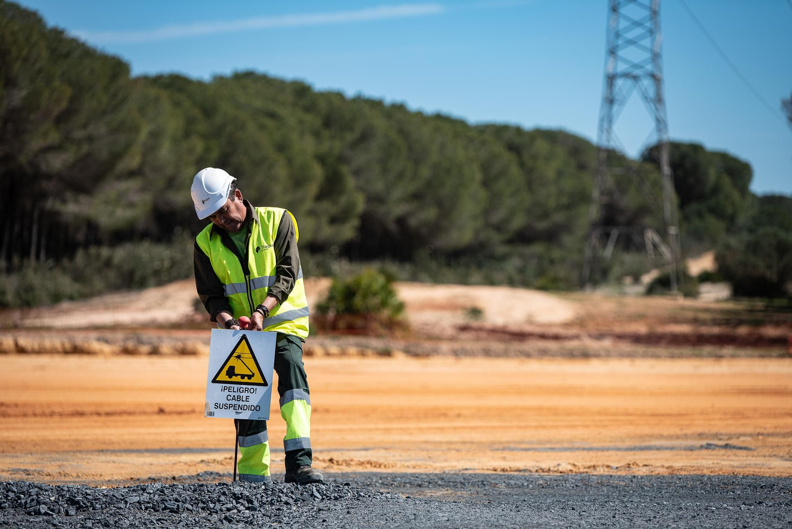 Un operario coloca un cartel con el aviso del cable en la pista del CEUS.