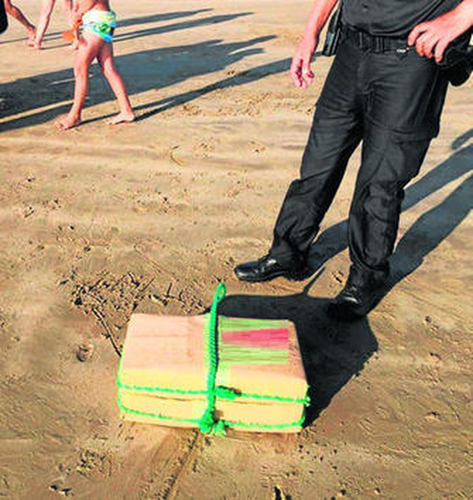 Un agente de Policía custodia uno de los fardos de 30 kilos de hachís recuperado en la playa de Cortadura.