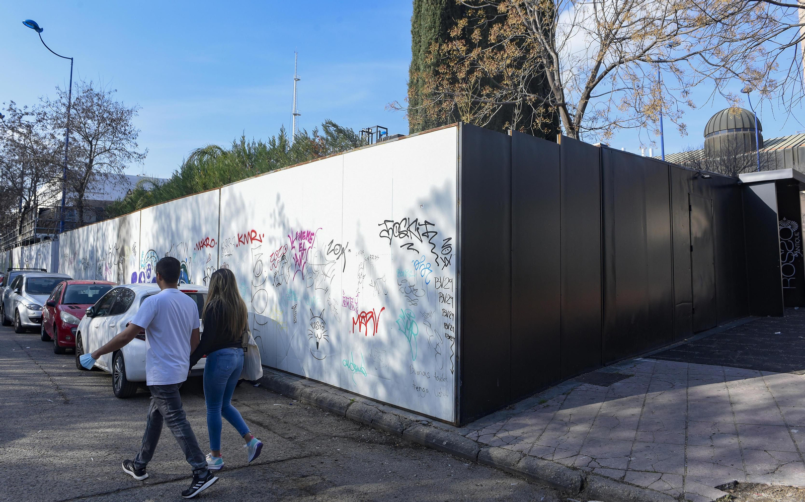 Una pareja camina por la calzada debido a que la acera se encuentra ocupada por el cerramiento de la discoteca.