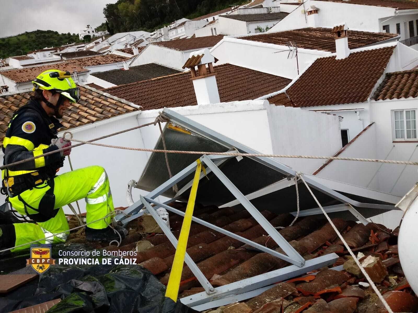 Uno de los bomberos retira las placas solares afectadas por el vendaval.