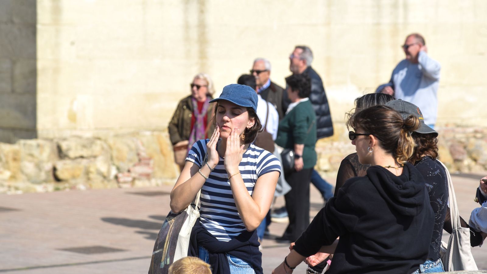 Una joven se echa crema en la cara para protegerse del sol.