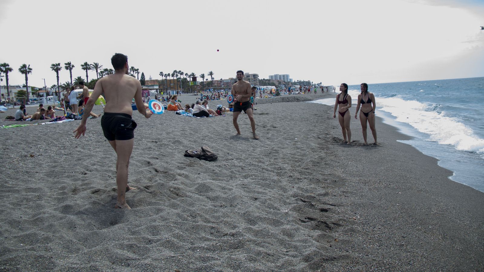 Varios jóvenes juegan a las palas en la playa de Salobreña
