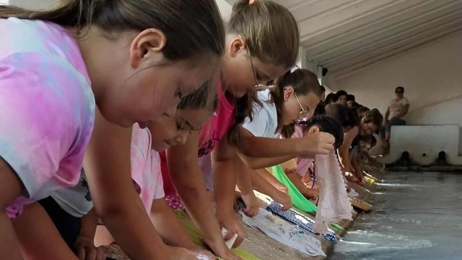 Niños frotando y aclarando la ropa con jabón.