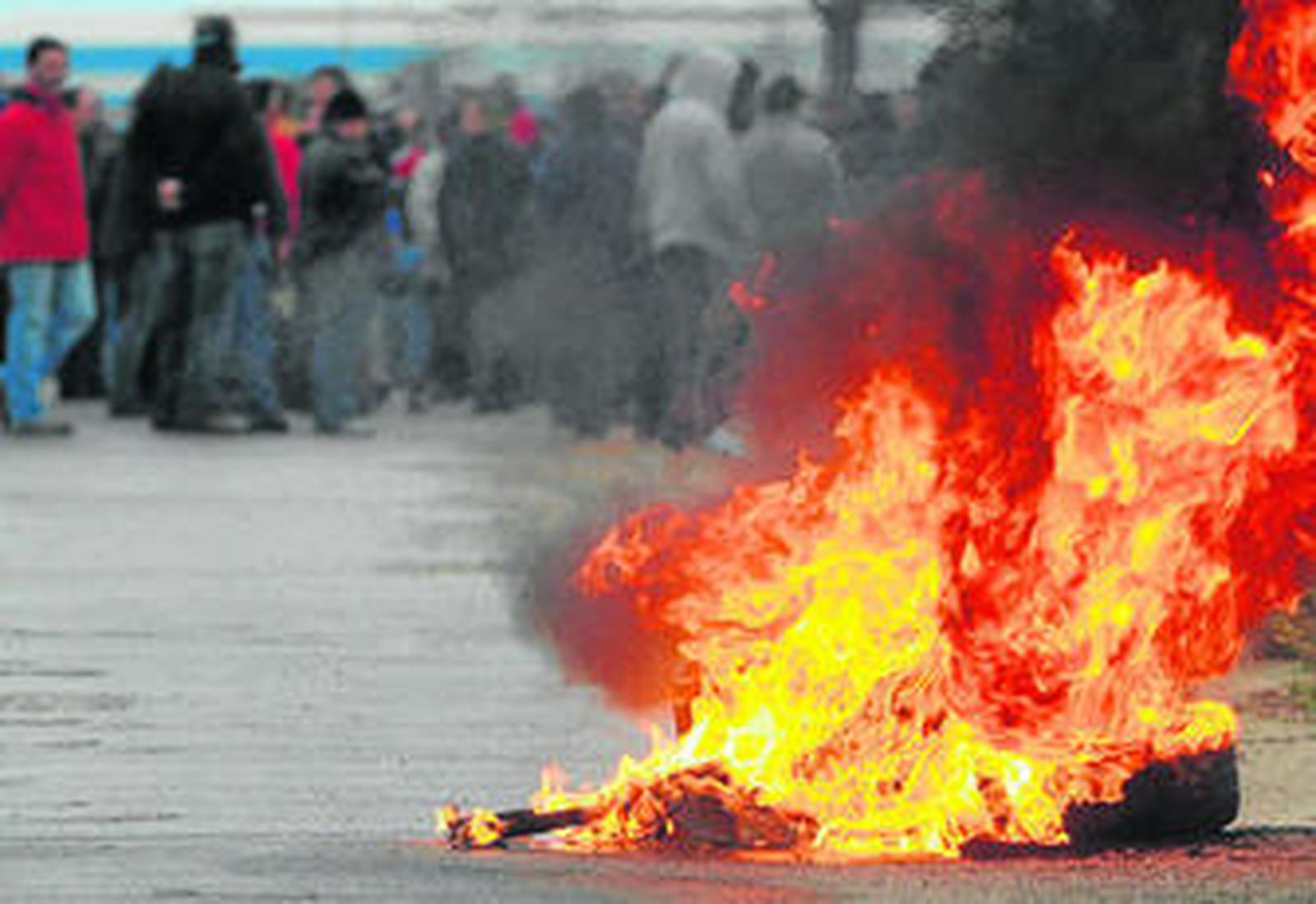 Varios neumáticos ardiendo en la puerta de la factoría de Delphi tras la reunión de los trabajadores celebrada el sábado.