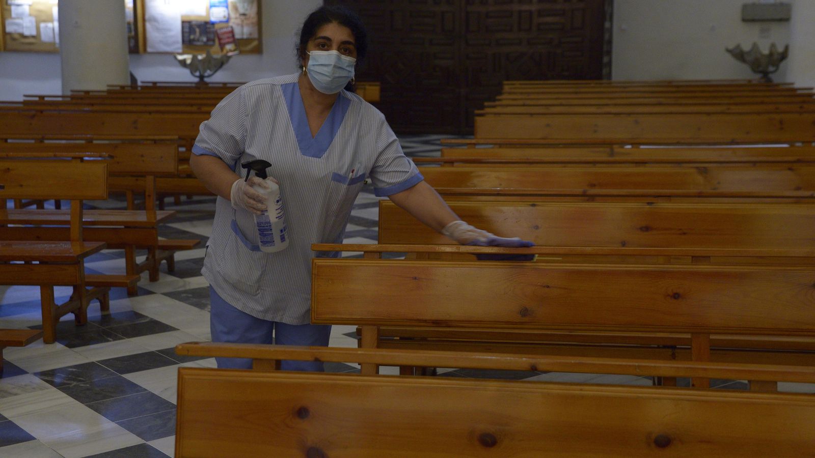 Una limpiadora desinfecta los bancos de la parroquia de La Palma, en Algeciras.