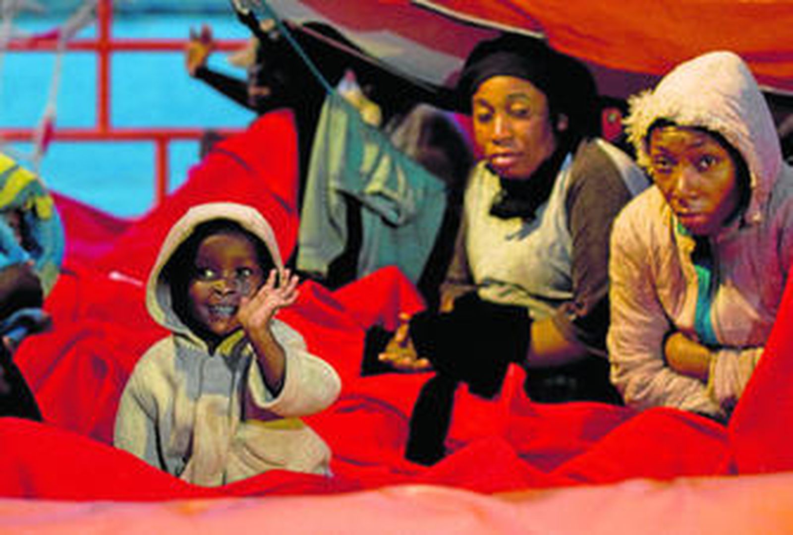 Uno de los menores de la patera saluda desde la embarcación de rescate.