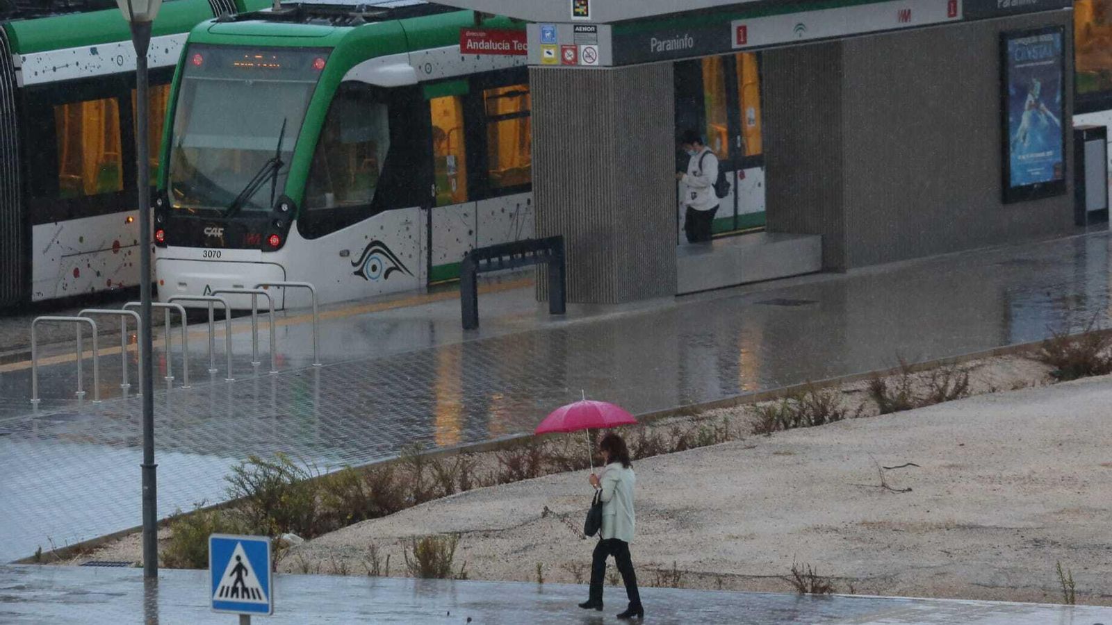 Una mujer, con paraguas, se dirige a la estación del metro de Málaga.