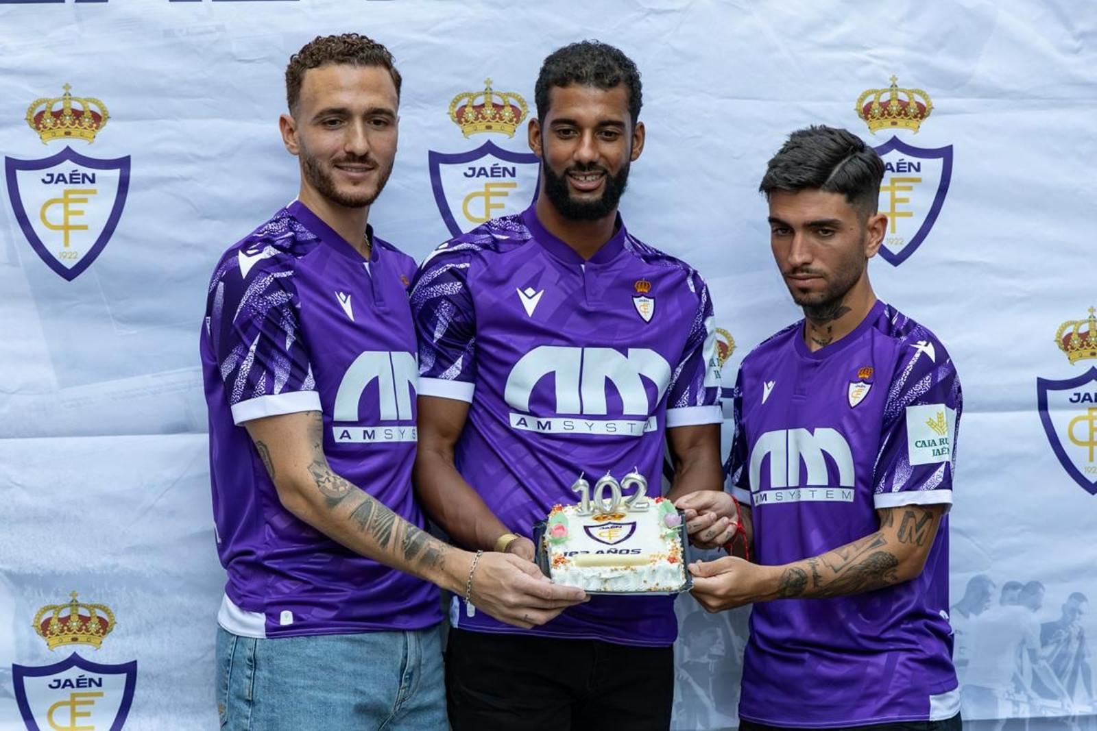 Agus Alonso, Pablo de Castro y Óscar Lozano posan con la tercera equipación y la tarta conmemorativa.