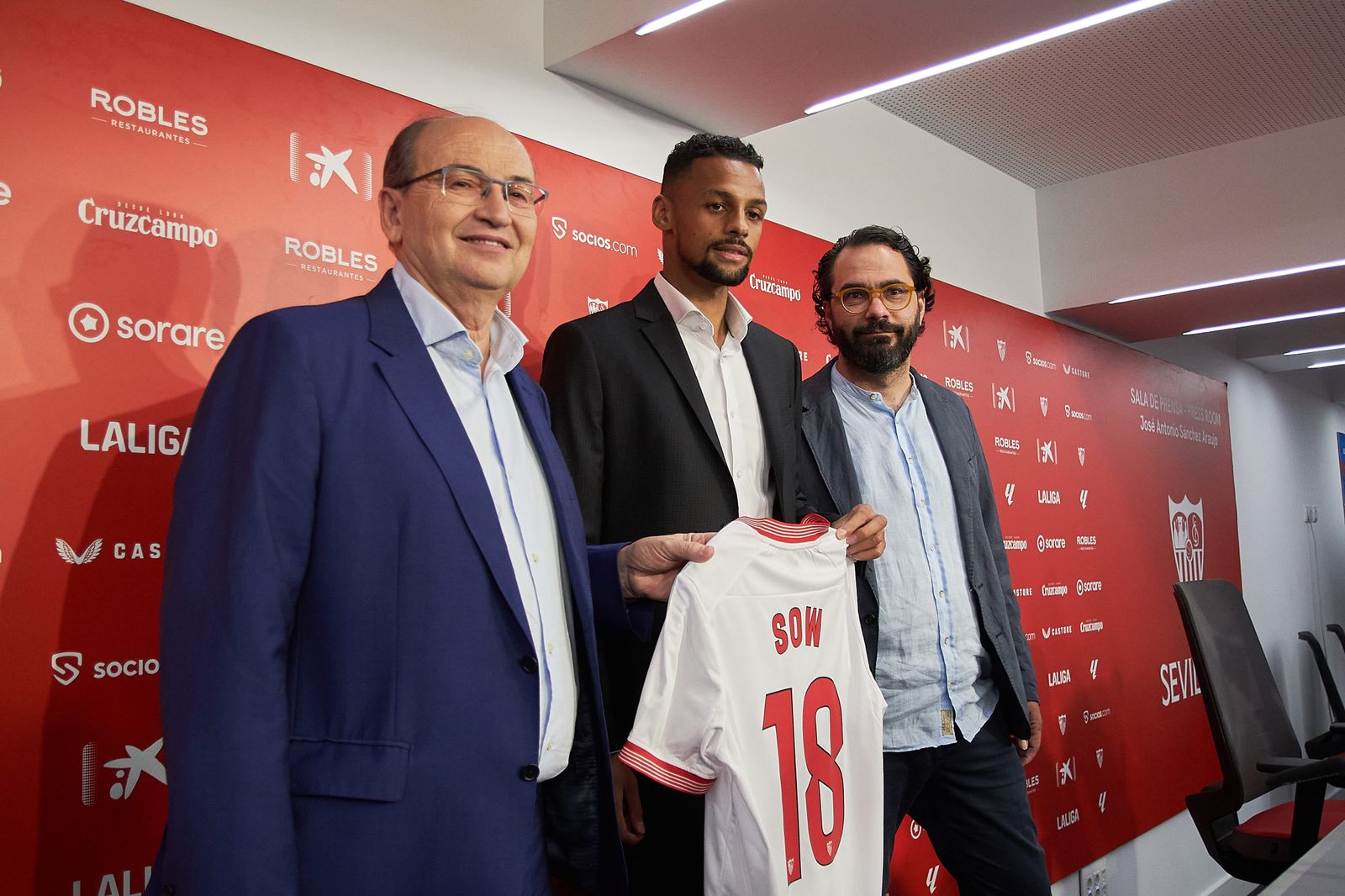 Djibril Sow posa con la camiseta del Sevilla entre José Castro y Víctor Orta.