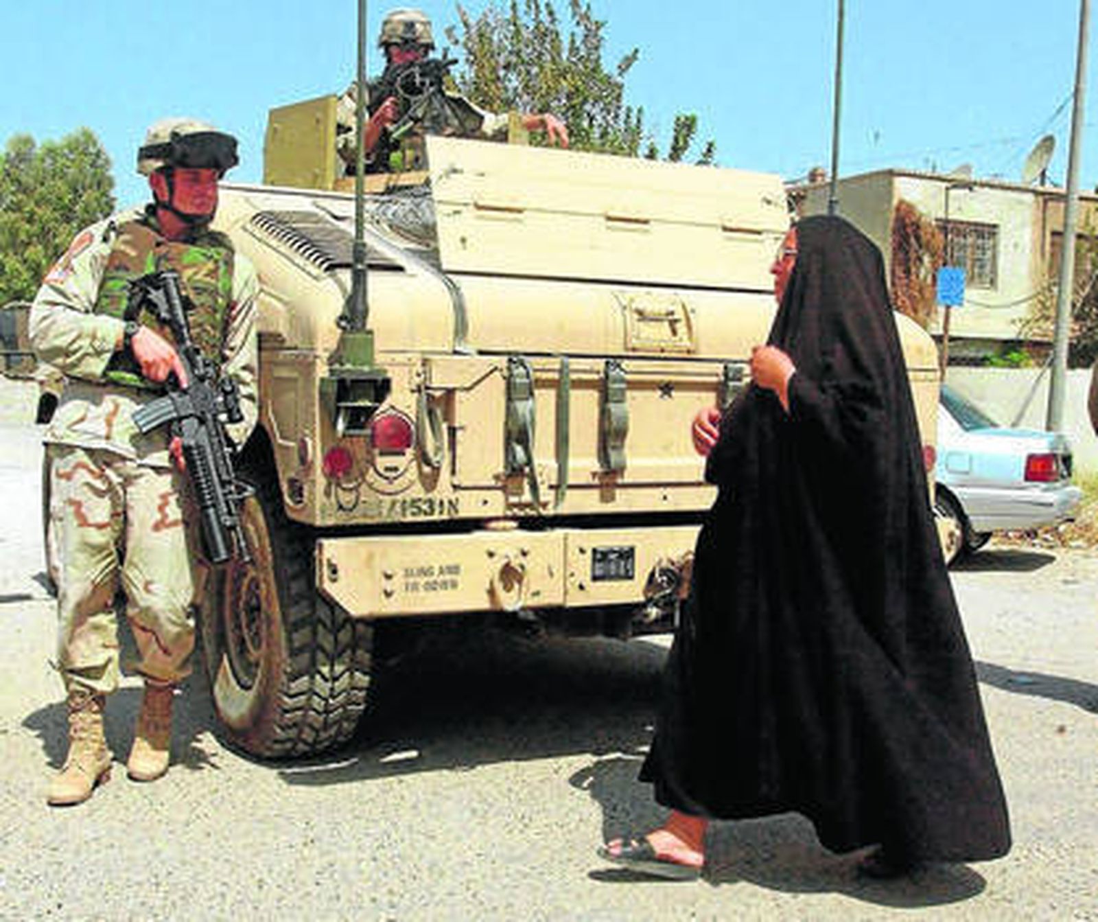 Fotografía de archivo de 2004, en la que una mujer iraquí que se cruza con soldados estadounidenses en Bagdad.