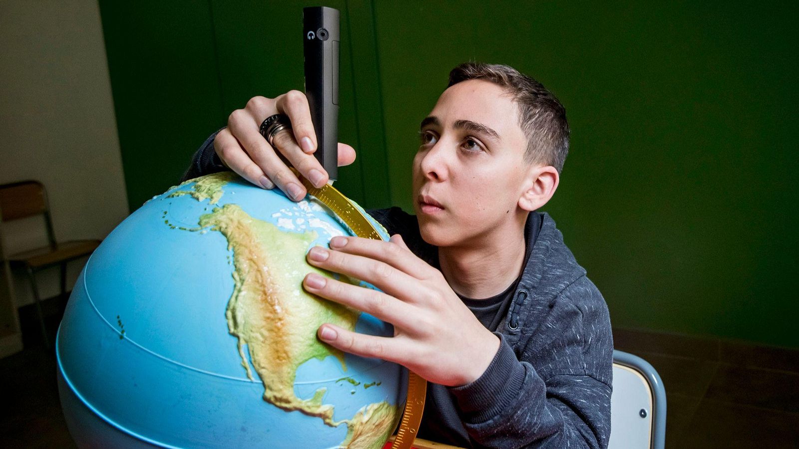 Un alumno con una bola del mundo adaptada