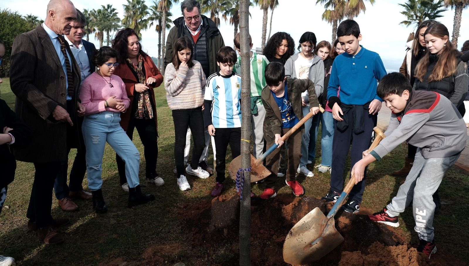 Niños y niñas del CEIP Rico Cejudo en las labores de plantación en el parque Vega de Triana, junto al alcalde y autoridades.