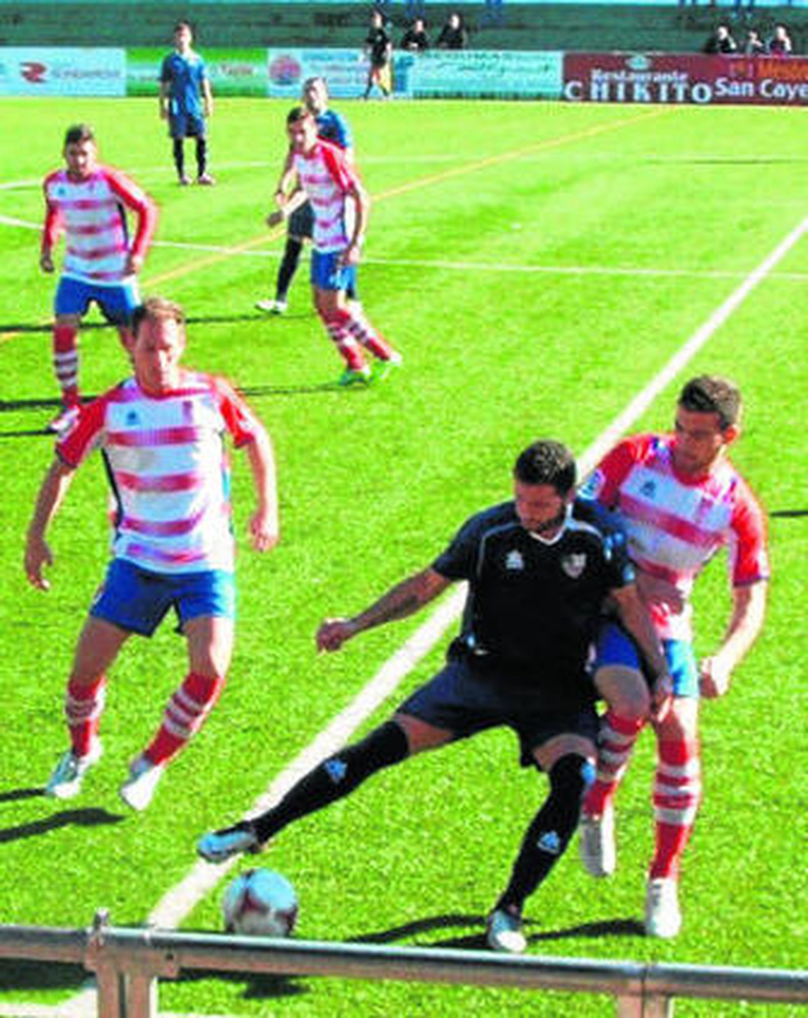 Domingo protege el balón ante dos rivales.