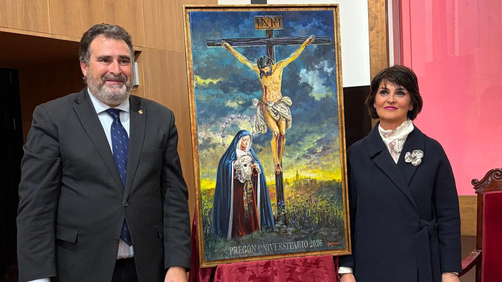 José Ignacio del Rey Tirado y Nuria Barrera flanquean el cartel anunciador del pregón universitario.