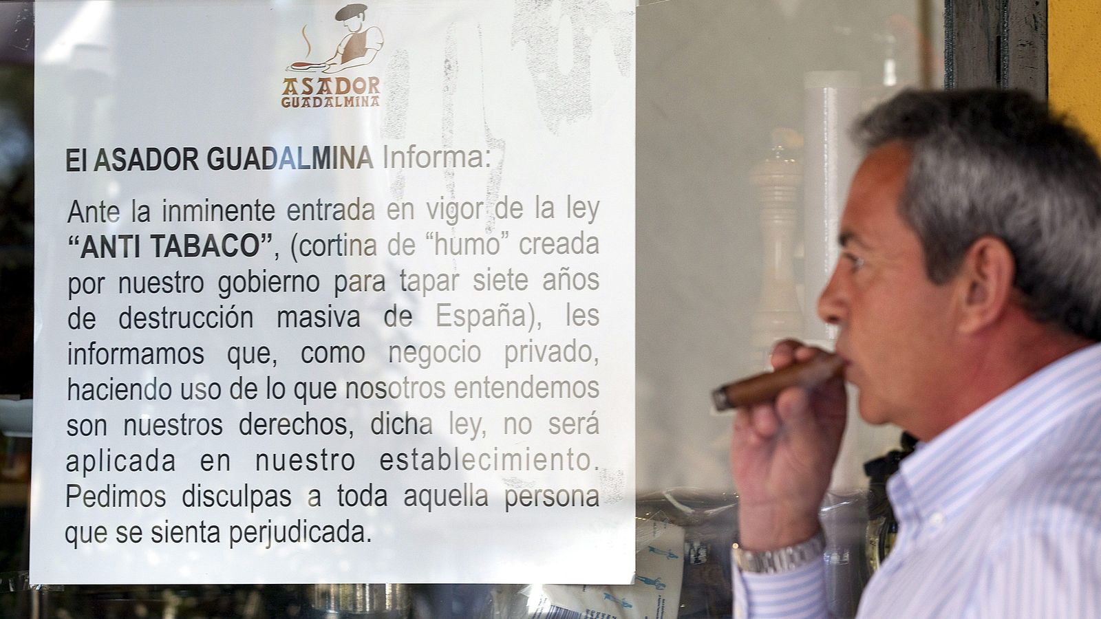 Un hombre fuma un puro fuera de un local.