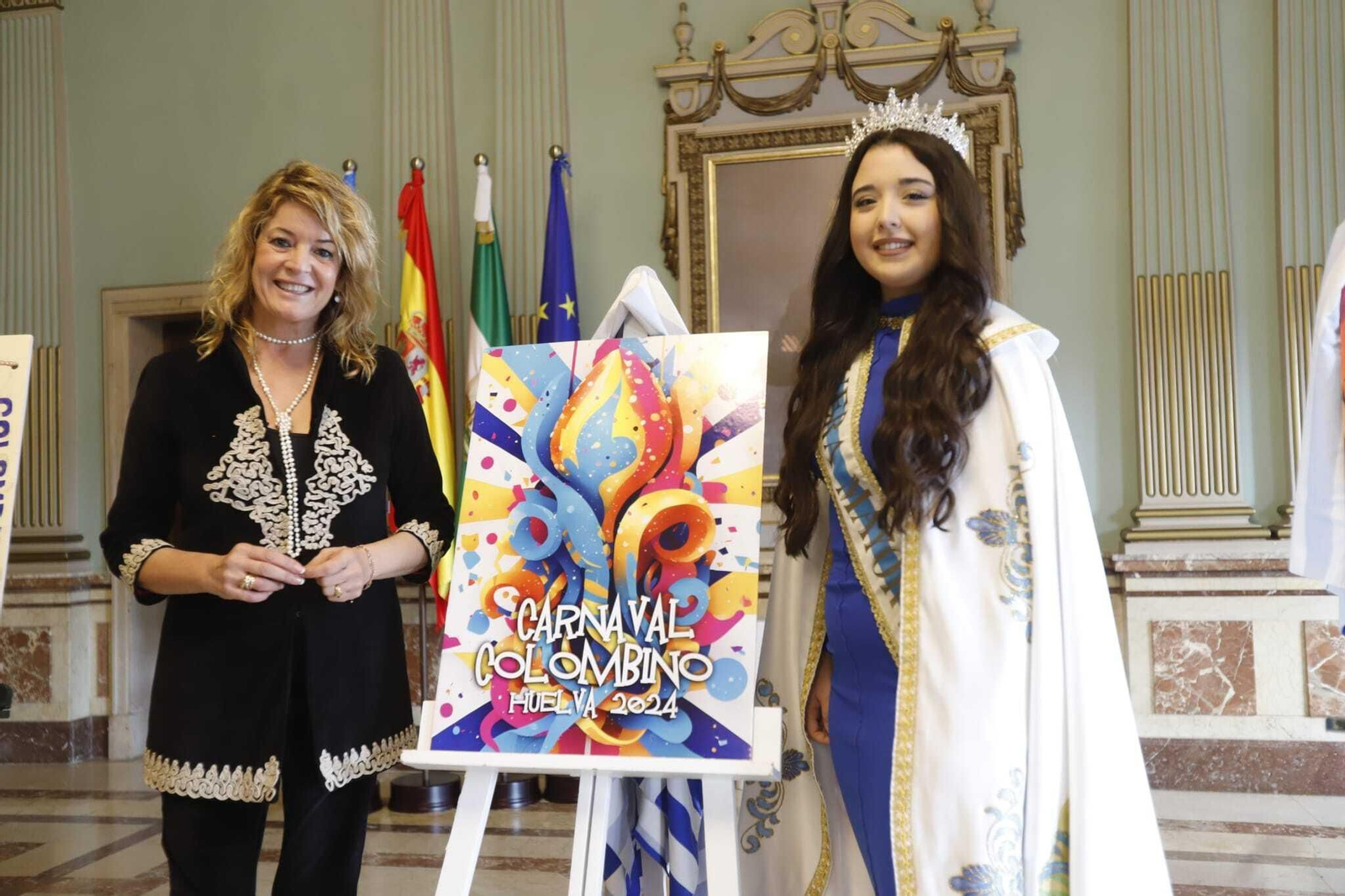 La alcaldesa de Huelva, Pilar Miranda, y la choquera mayor, Andrea Sánchez, junto al cartel