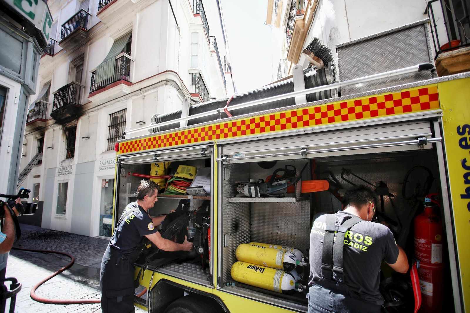 Dos bomberos guardan el material empleado en la extinción del incendio en su vehículo.