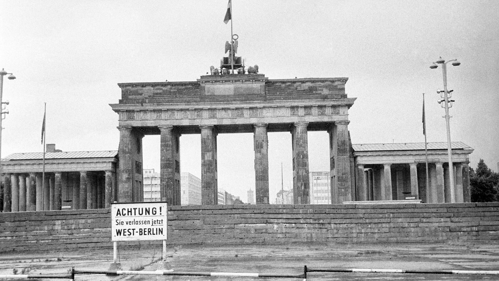 La Puerta de Branderburgo en la época del Muro de Berlín con un cartel en el que pone "¡Atención! Está saliendo de Berlín Oeste".