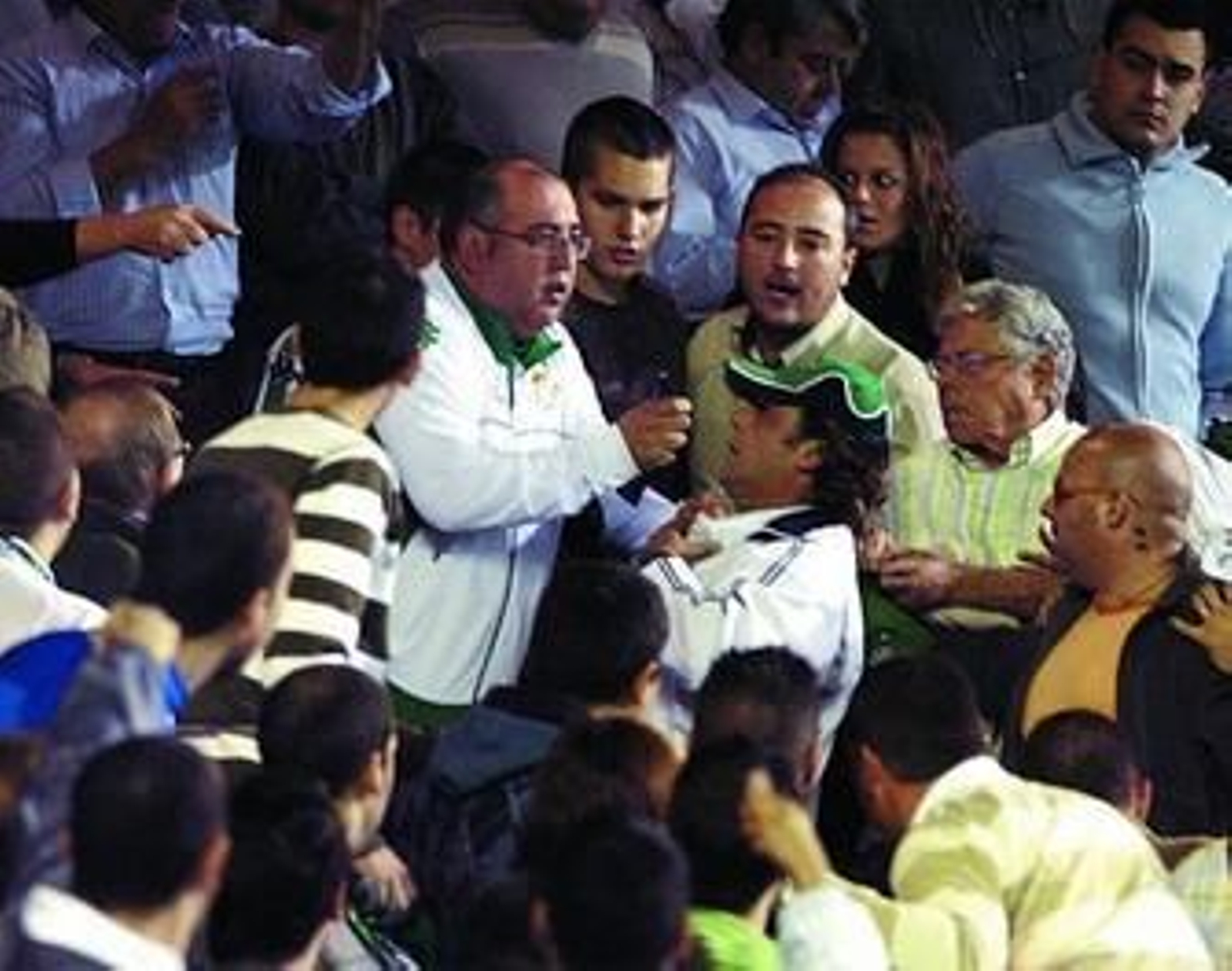 El supuesto agresor, con gorra, es reprendido por un aficionado tras lanzar la botella.