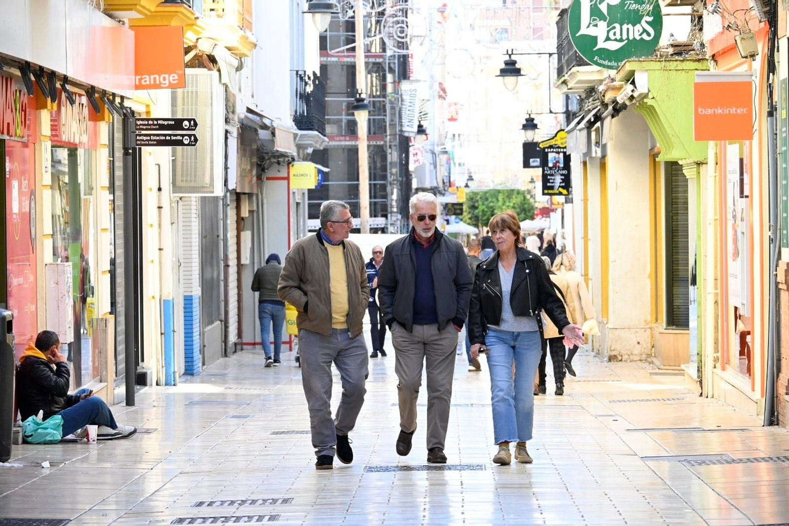 Varias personas pasean con chaquetones por el centro de Huelva.