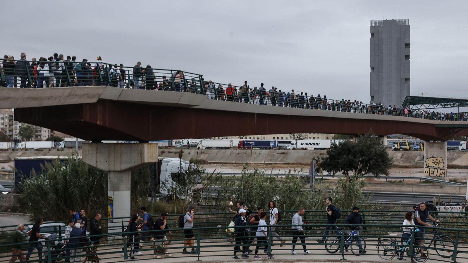 Decenas de personas en el puente que une Valencia con La Torre, donde centenares de personas llegan de Valencia de abastecerse de agua y alimentos mientras otras salen de ayudar, en Valencia.