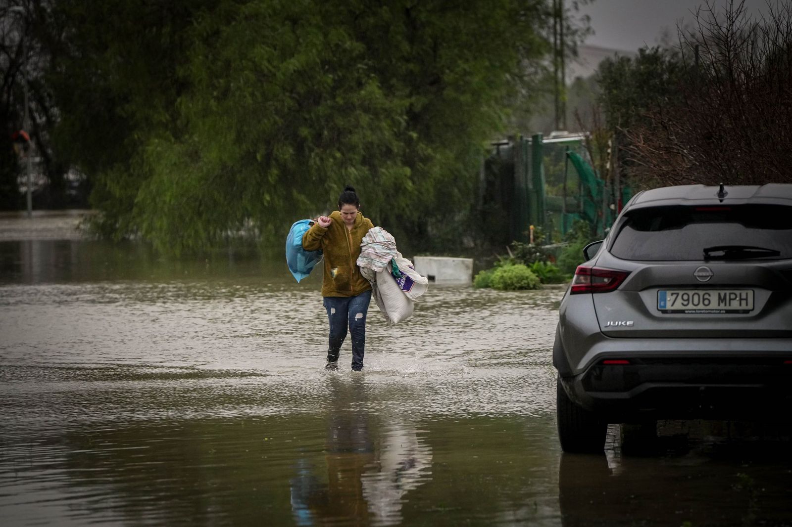 Una mujer sale con algunas de sus pertenencias de su vivienda en Las Pachecas que se ha visto afectada por la crecida del río.