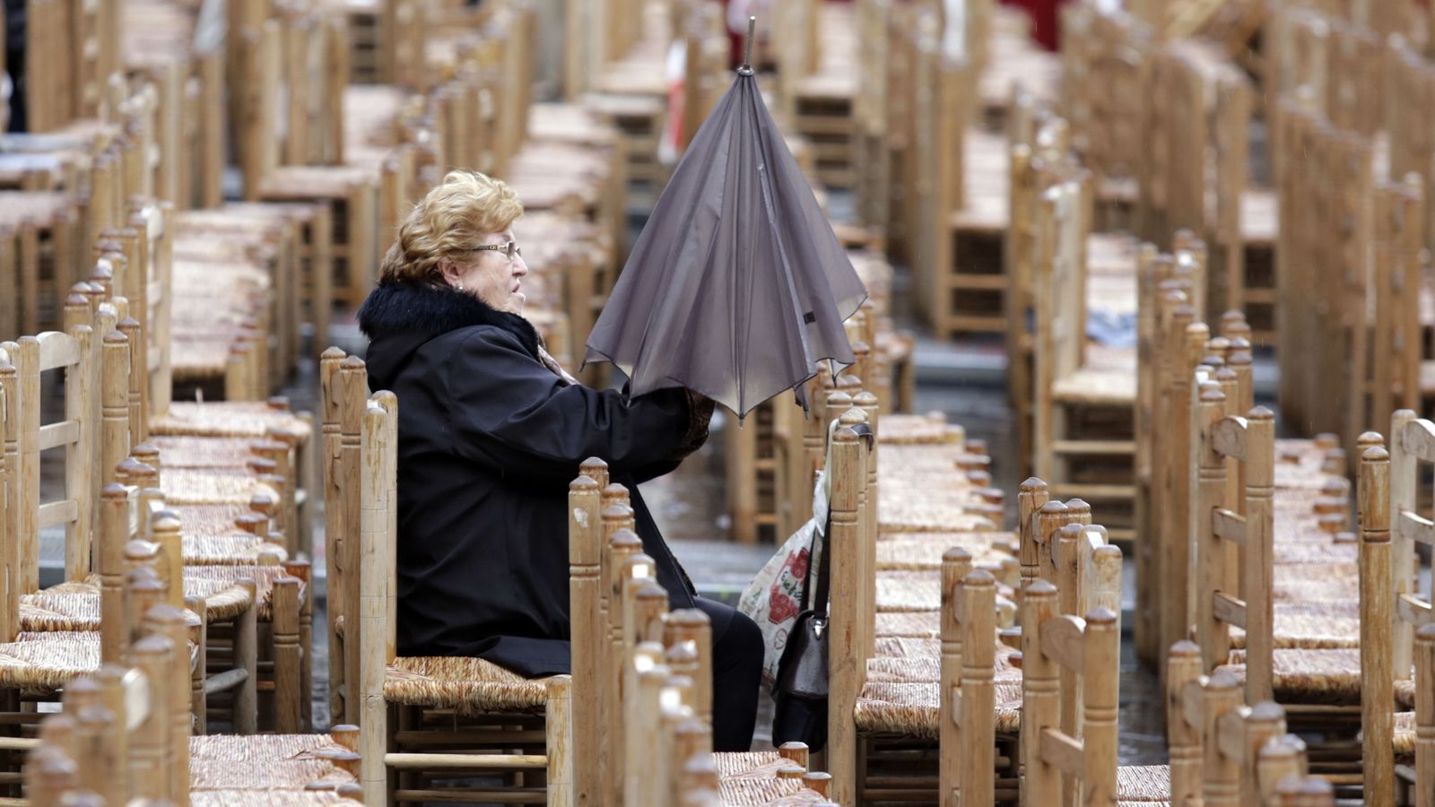 Una mujer ocupa una silla en la Plaza de la Campana tras una jornada lluviosa.