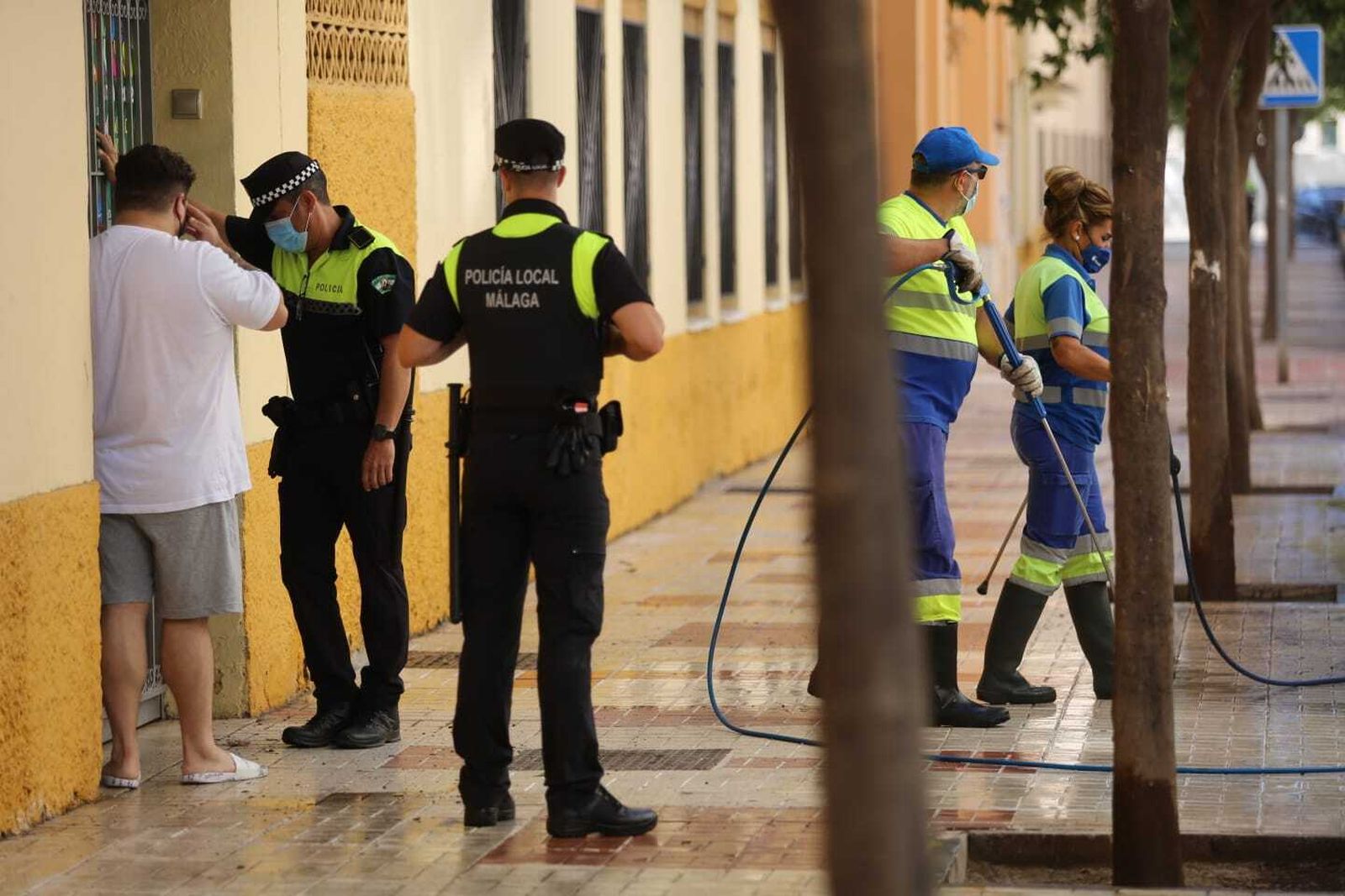 Policía junto a operarios de limpieza en la puerta del colegio.