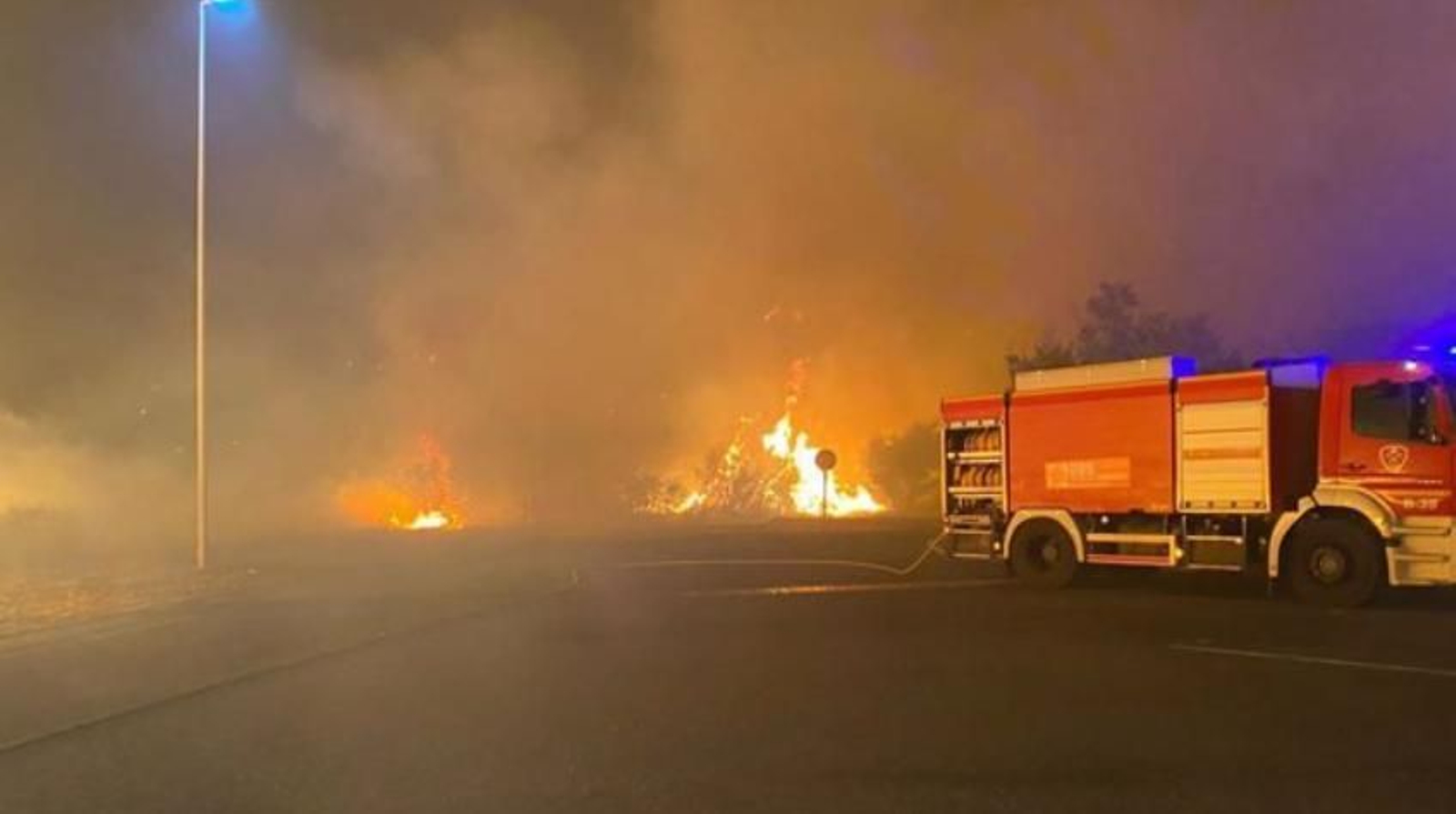 Un camión de bomberos junto a las llamas