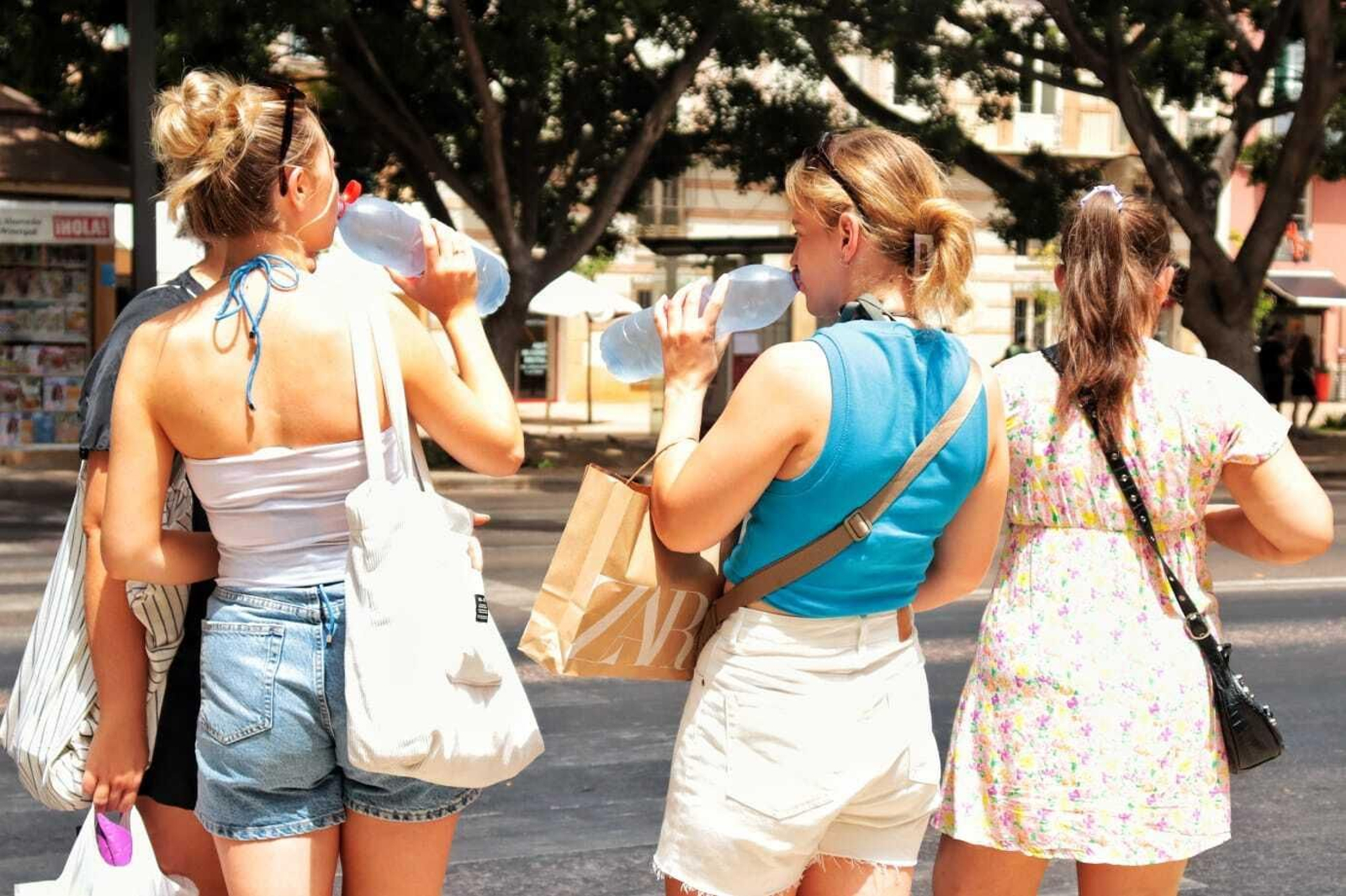 Dos mujeres beben agua para hidratarse frente al calor.