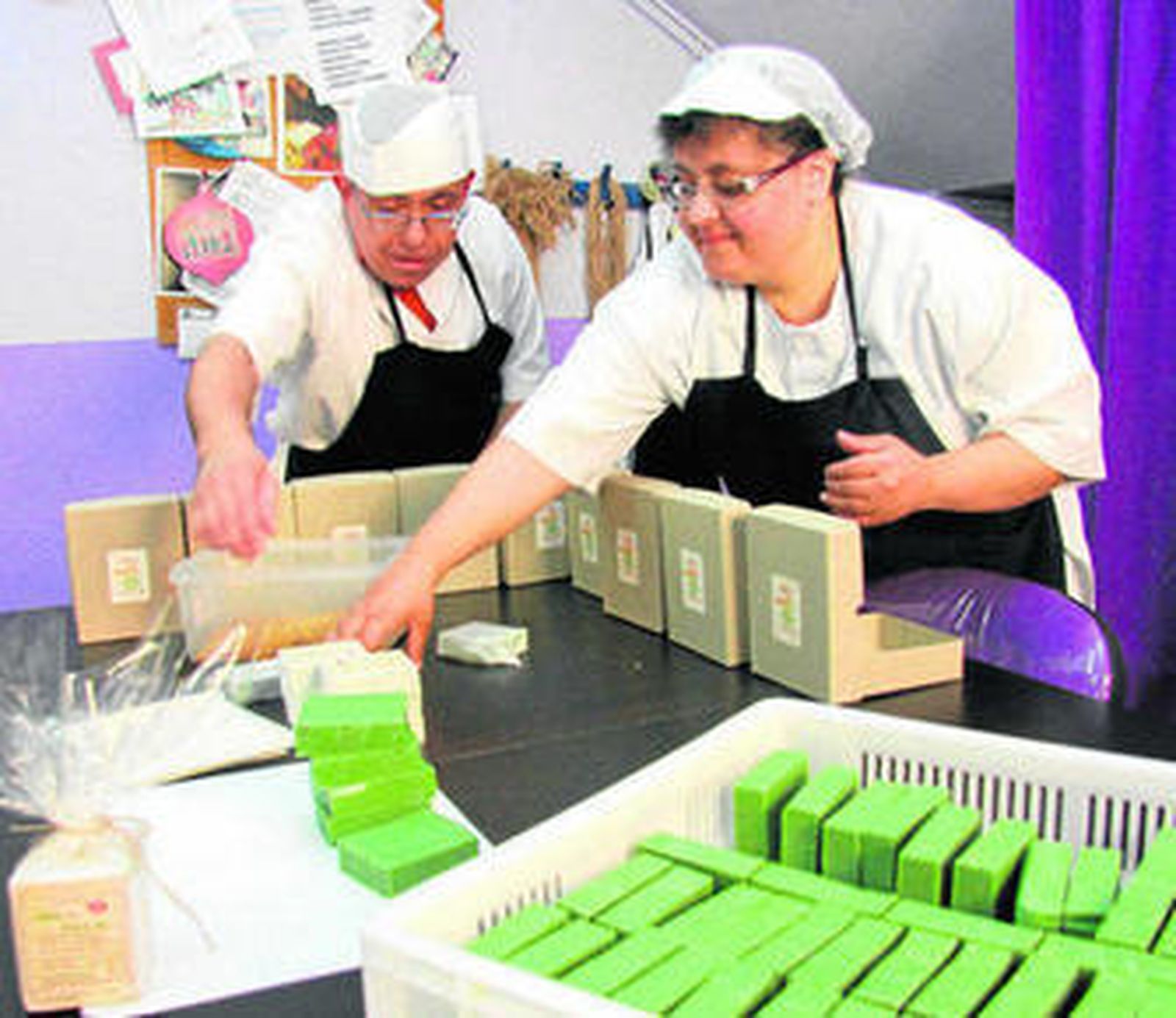 Dos trabajadores con discapacidad envasan jabones en Los jabones de Afim en Málaga.
