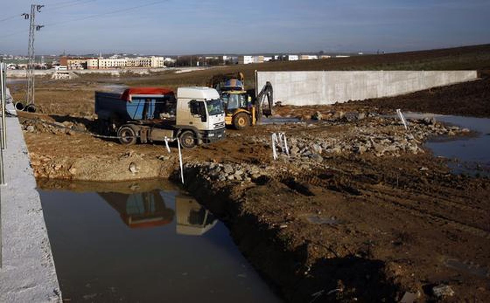 Los trabajadores construyen el nuevo dique colocando las 37 toneladas de piedra de escollera, transportadas por el camión, para evitar que la abundante agua del arroyo inunde Écija de nuevo.

Foto: Antonio Pizarro
