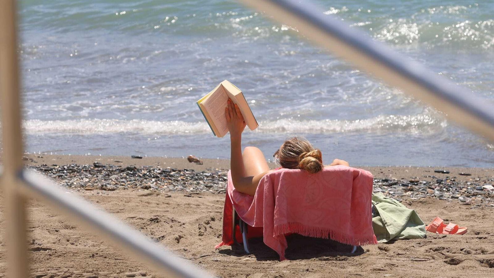 Una joven lee un libro mientras toma el sol en Málaga.