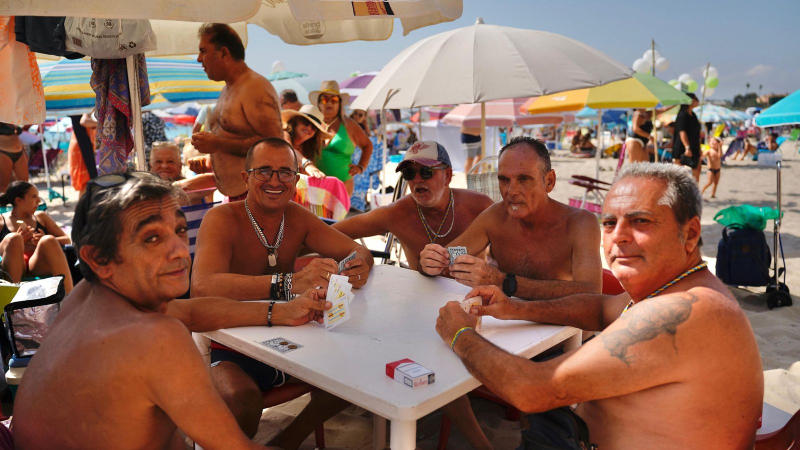 Cuatro hombres hacen tiempo jugando a las cartas en la playa. Cuatro hombres hacen tiempo jugando a las cartas en la playa.