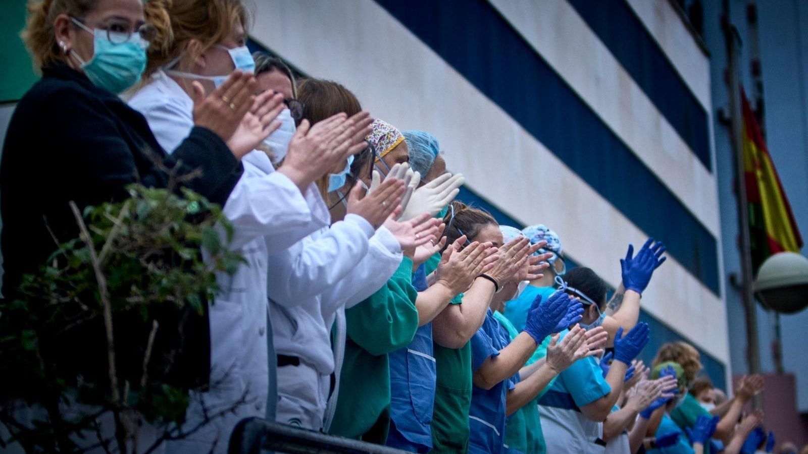 Un grupo de sanitarios aplaudiendo en el exterior del Puerta del Mar.