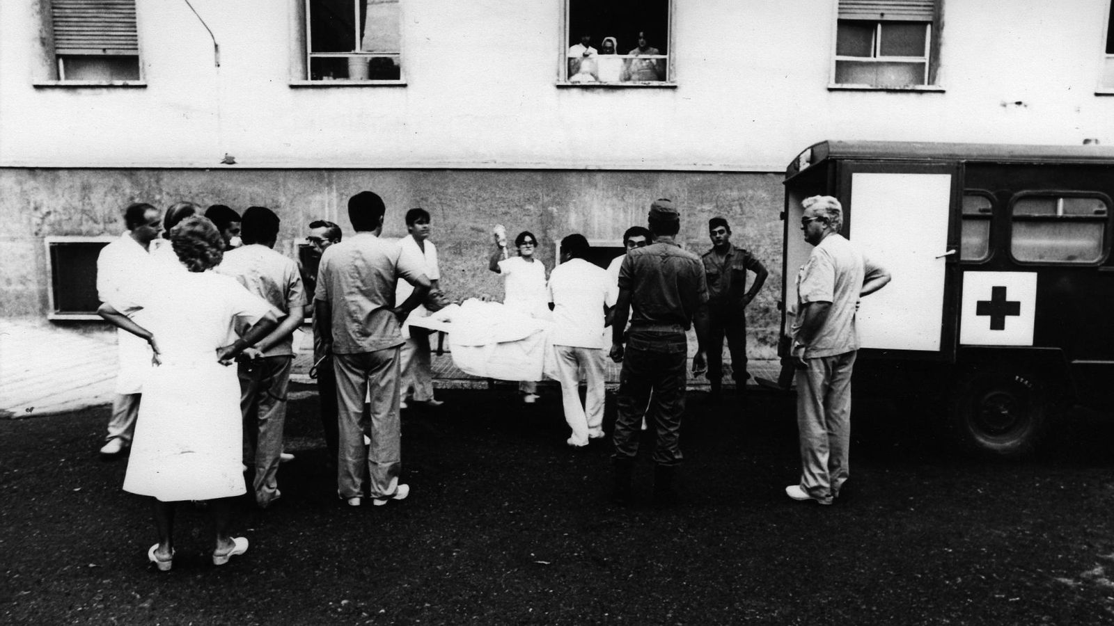Una nube de enfermeros y médicos introducen en una ambulancia del ejército a un paciente de la Bola Azul