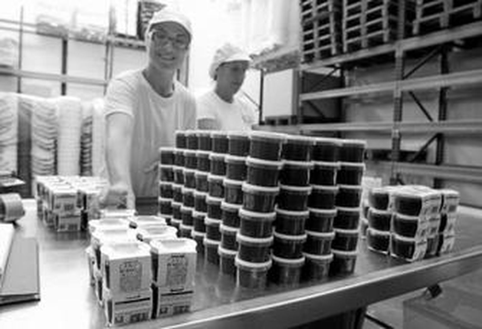Dos trabajadoras empaquetan varios botes de carne de membrillo en la fábrica situada en Pizarra.