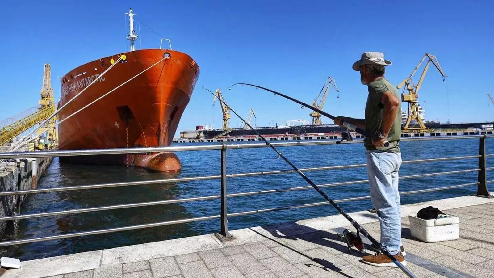 Un pescador, con su caña, a muy pocos metros de uno de los buques que repara en el astillero gaditano de Cádiz capital Un pescador, con su caña, a muy pocos metros de uno de los buques que repara en el astillero gaditano de Cádiz capital