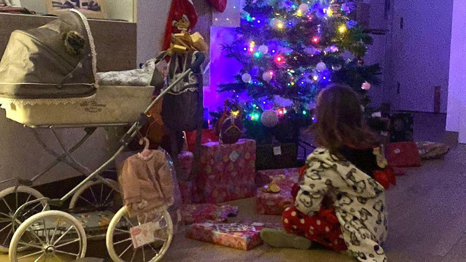 Una niña contempla el árbol de Navidad antes de abrir sus regalos.
