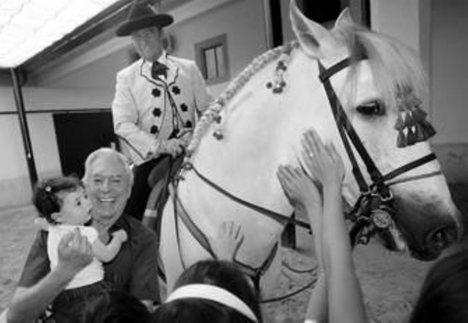 Mario Vargas Llosa sostiene a su nieta ante el jinete Ignacio Rambla montado a caballo ayer.
