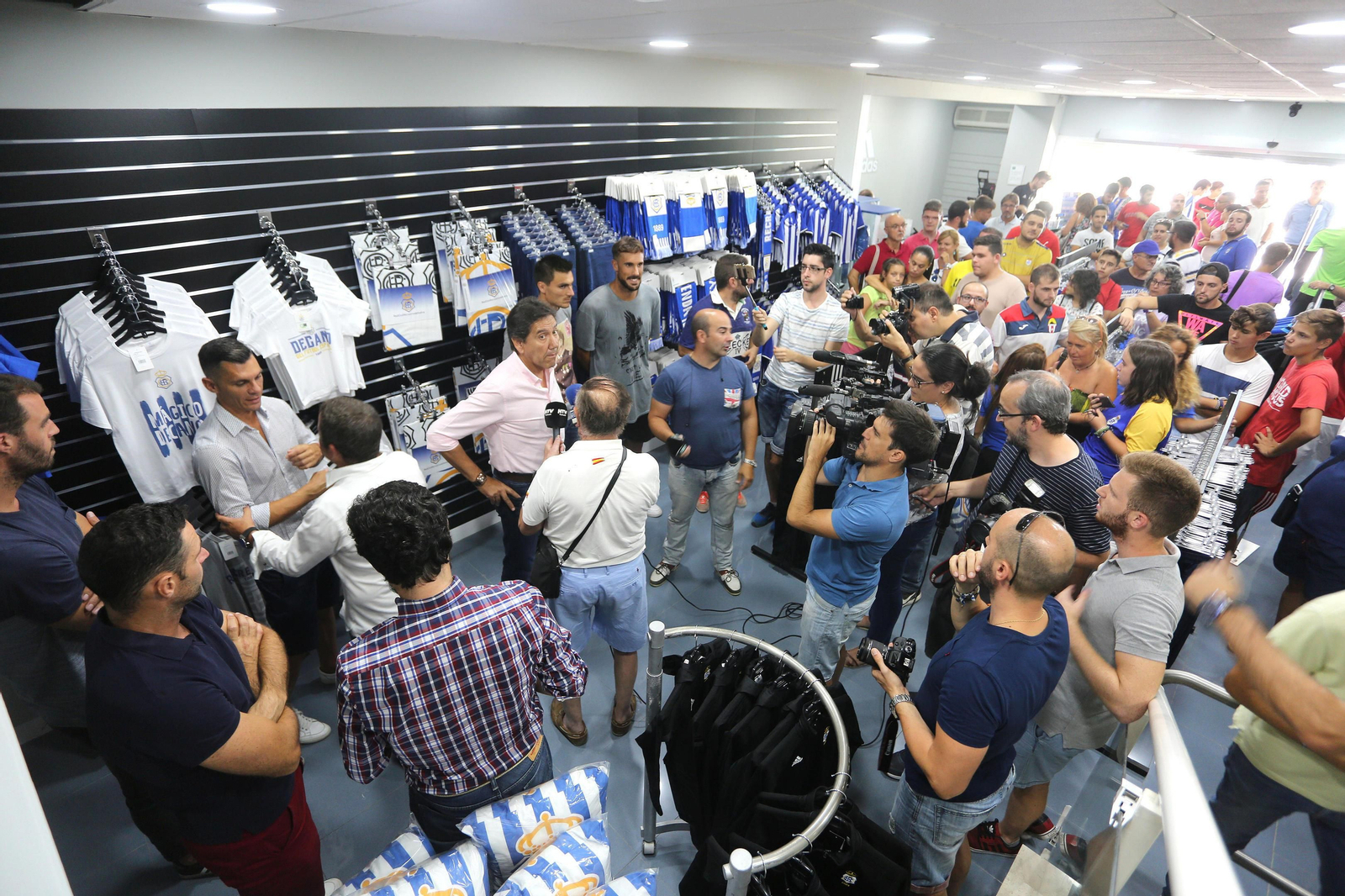 1. Masiva presencia de aficionados en la inauguración de la tienda. 2. Un seguidor compra una camiseta y unas tazas. 3. Puerta de entrada a la nueva tienda oficial del club. 4. Mucho movimiento en las primera jornada de la nueva tienda. 5. Amplia representación albiazul en la inauguración.