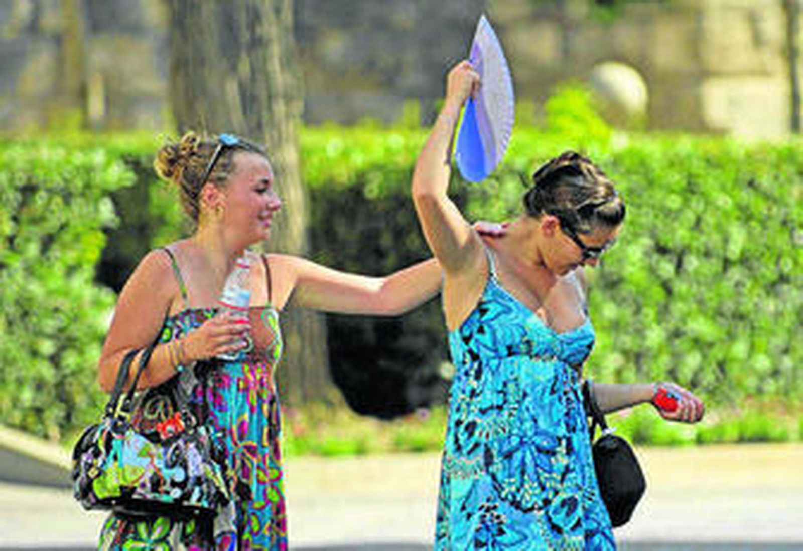 Dos jóvenes se alivian, con agua y abanico en mano, del calor de ayer.