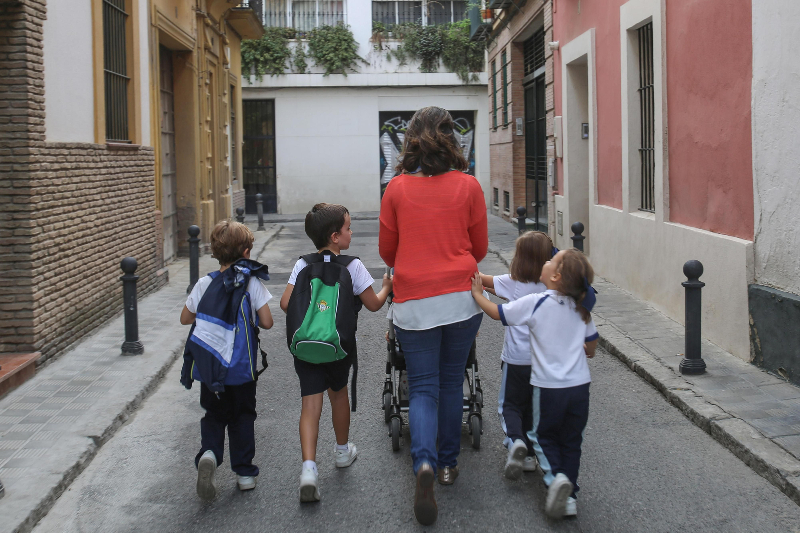 Una madre con cinco niños paseando por una calle de Sevilla.