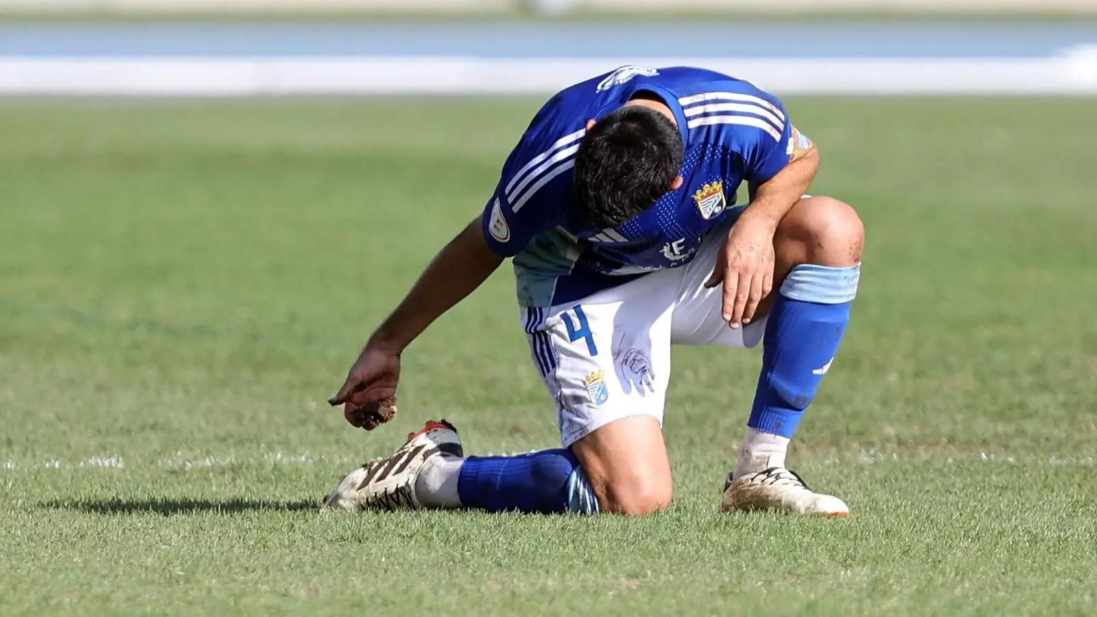 Adri Rodríguez, capitán del Xerez CD, retira de su bota acumulado en el césped de Chapín, en pésimo estado.