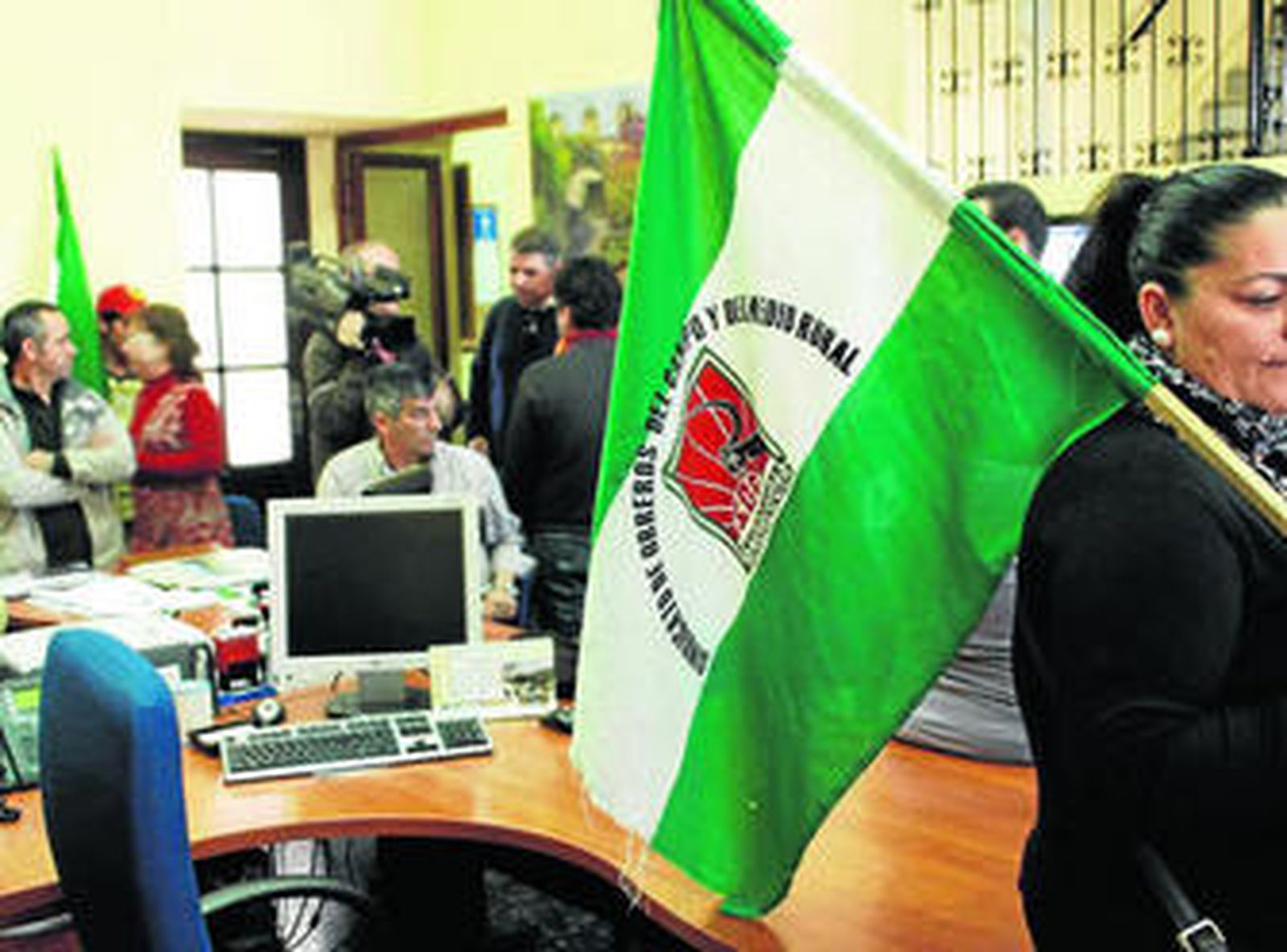 Una jornalera, con una bandera sindical, junto a una de las mesas vacías del Ayuntamiento de Bornos.